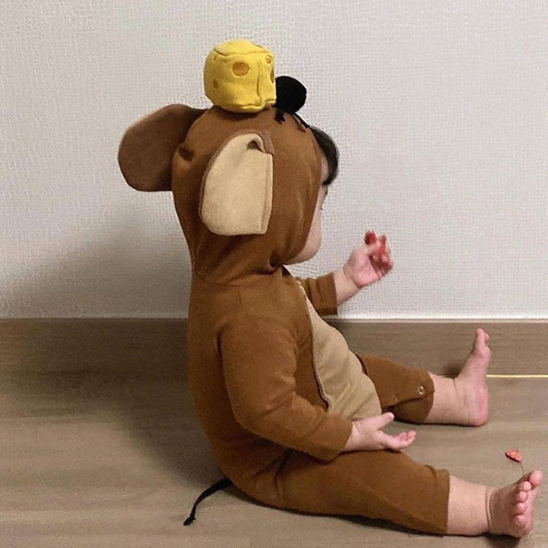 A toddler in a brown puppy costume with ears and a cheese hat sits on a wooden floor against a wall, playing.