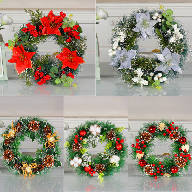 Five festive wreaths displayed, each adorned with varied decorations: red flowers, pinecones, ribbons, white berries, and ornaments, on a reflective surface.