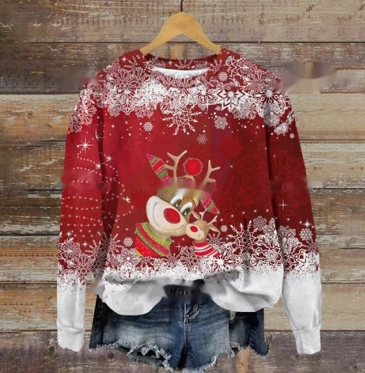 Red holiday sweater with white snowflake design featuring two cartoon reindeer in festive scarves. Paired with denim shorts, it hangs against a rustic wooden background.
