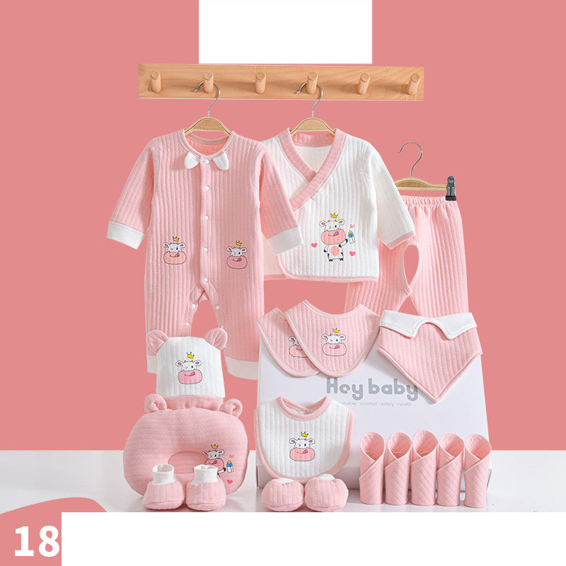 Baby clothing set in pastel pink and white featuring cow motifs. Includes a romper, jacket, pants, bibs, mittens, booties, a pillow, and a towel, all arranged against a pink wall.