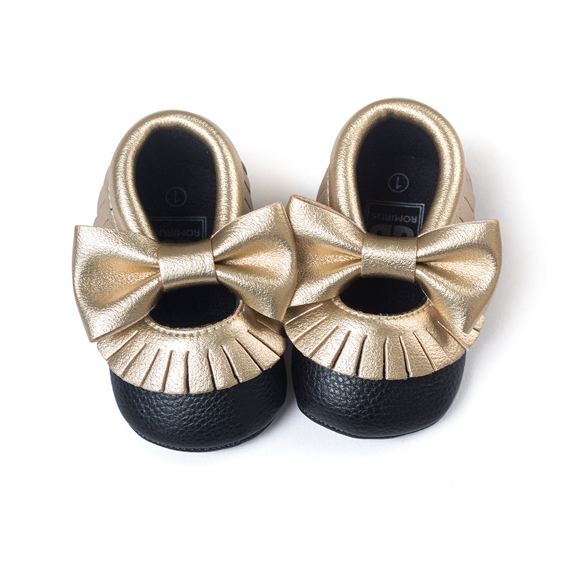 Gold and black baby moccasins with large gold bows, featuring fringe detailing around the edges.