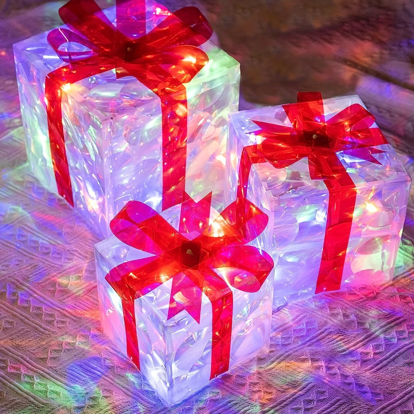 Three glowing gift boxes with red ribbons, each emitting colorful lights, placed on a textured surface. The lights create a vivid, festive ambiance.