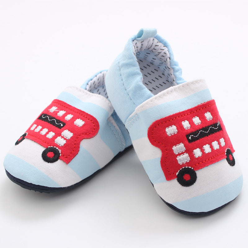 Blue and white striped baby shoes with red double-decker bus applique on top. The interior features a soft, patterned lining.