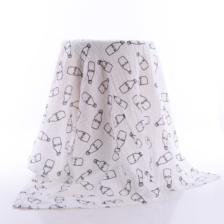White fabric draped over a surface, featuring a pattern of illustrated milk bottles with "milk" written on them. The background is plain white, highlighting the fabric design.