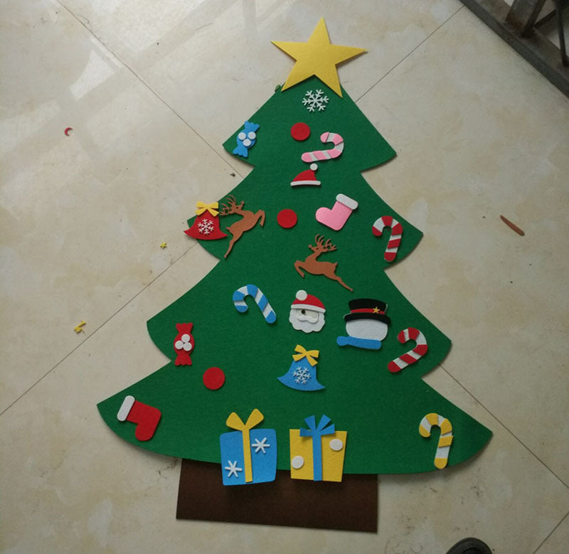 A felt Christmas tree on a tiled floor, decorated with cutouts: a yellow star, candy canes, reindeer, snowman, gifts, bells, and stockings in festive colors.