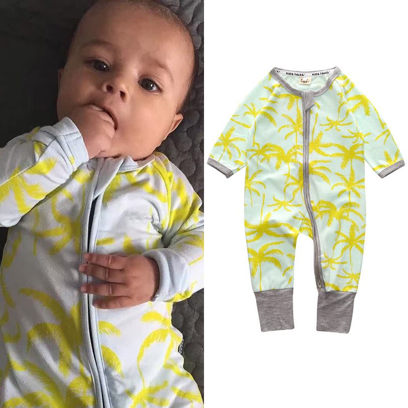 Baby wearing a light blue and yellow palm tree print onesie, sucking on fingers, lying down. On the right, the same onesie shown with a gray trim and zipper.