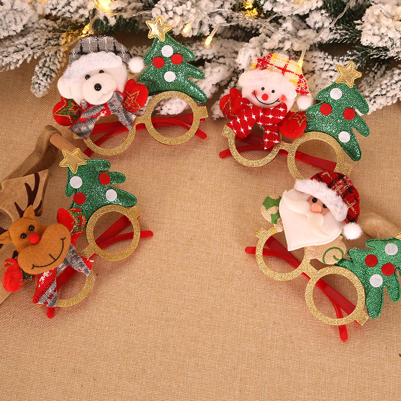 Christmas glasses adorned with festive characters—snowman, reindeer, bear, and Santa—featuring glittery green trees. Set against a snowy backdrop with warm lights.