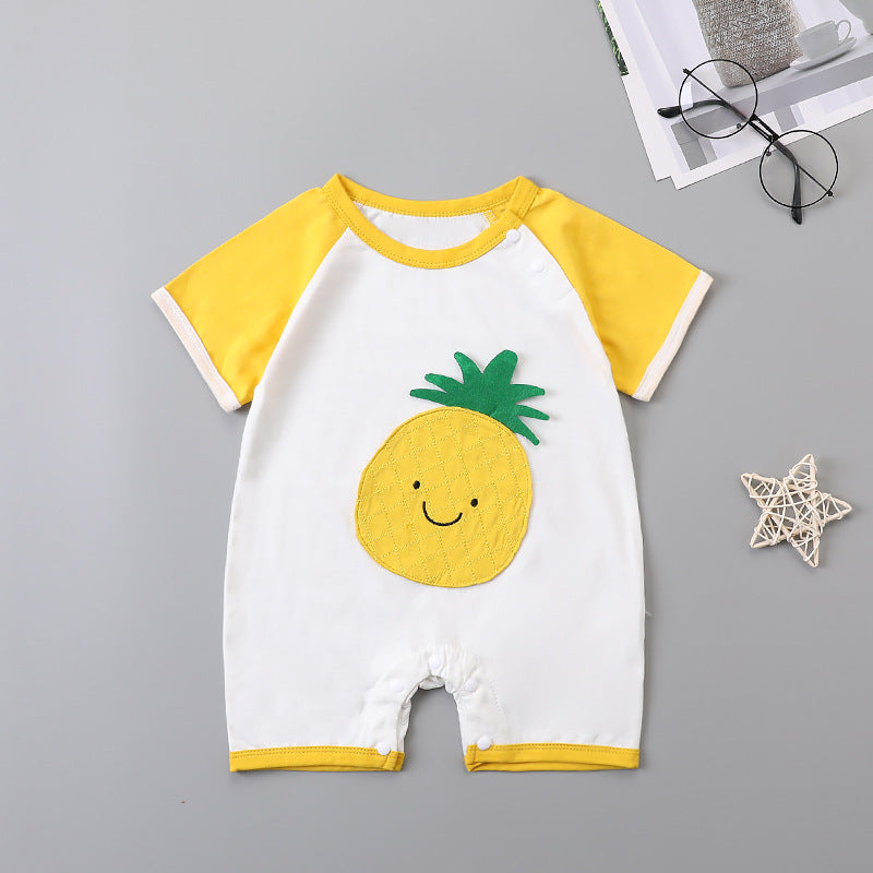Cute baby romper with white body, yellow sleeves, and a smiling pineapple design on the front. Nearby, black glasses and a woven star decoration rest on a gray surface.