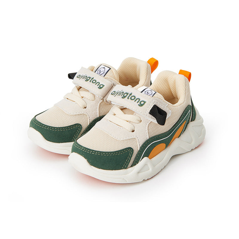 Beige and green kids' sneakers with Velcro straps, orange accents, and a chunky white sole. The brand name is on the strap, and there's a small tag on the tongue.