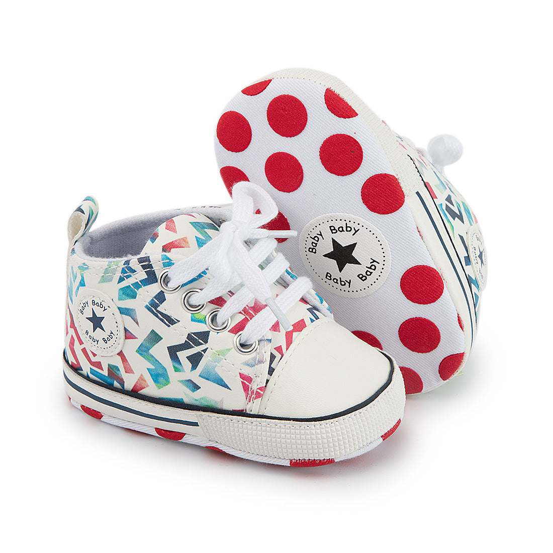 Colorful baby sneakers with a geometric pattern and white laces. The soles feature large red polka dots, and branding text with a black star logo.