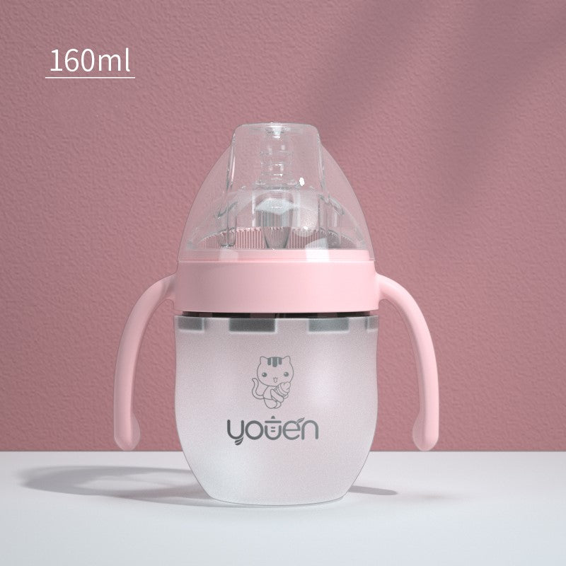 A 160ml frosted baby bottle with pink handles and a clear lid sits against a pink textured wall. It features a cute kitten design and the word "youen" on the front.