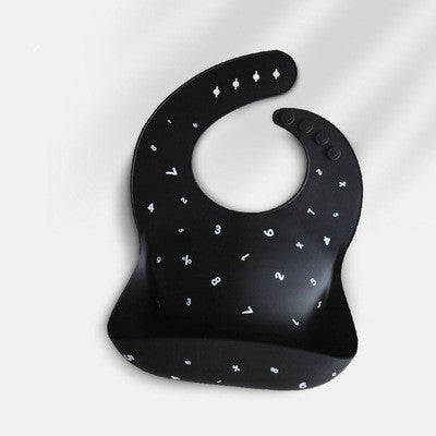 Black silicone baby bib with white letters and numbers scattered across its surface. The bib has an adjustable strap with buttons and a deep pocket for catching spills.
