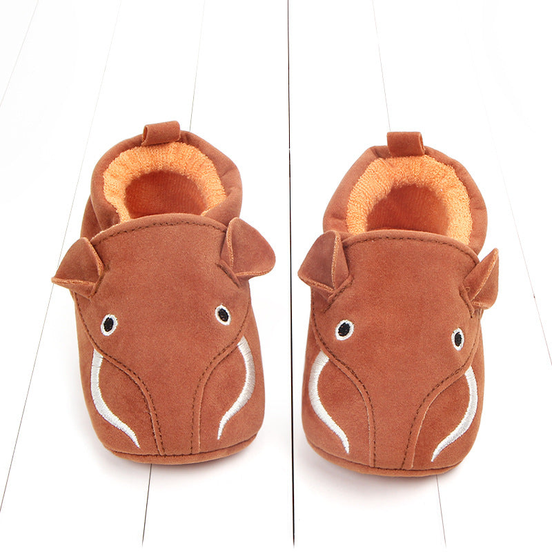Brown children's slippers with a cute animal face design, featuring eyes and ears, on a white background. The interior lining is orange and plush for added comfort.