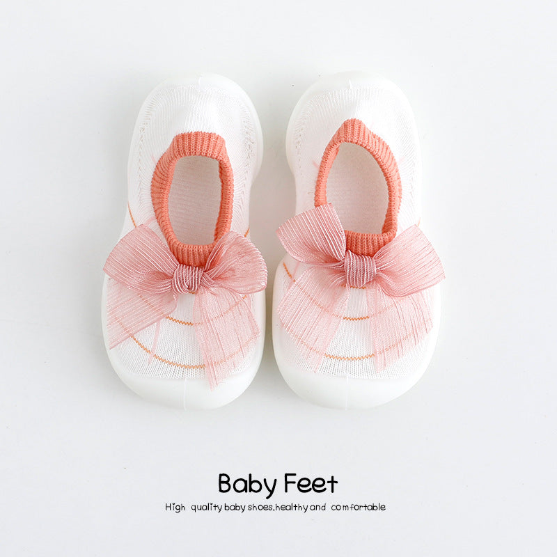 White baby shoes with pink bows and trim, featuring a knitted texture. The text "Baby Feet" is printed below, promoting high-quality, healthy, and comfortable footwear.