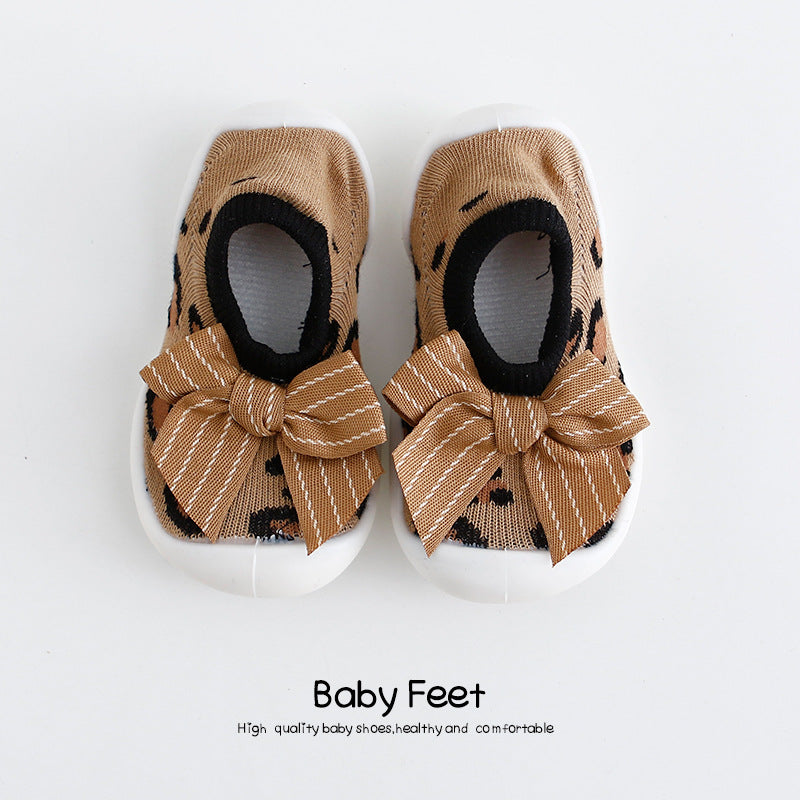 Brown baby shoes with white soles and leopard print, featuring large decorative bows. Text below reads "Baby Feet," indicating high quality, healthy, and comfortable footwear.
