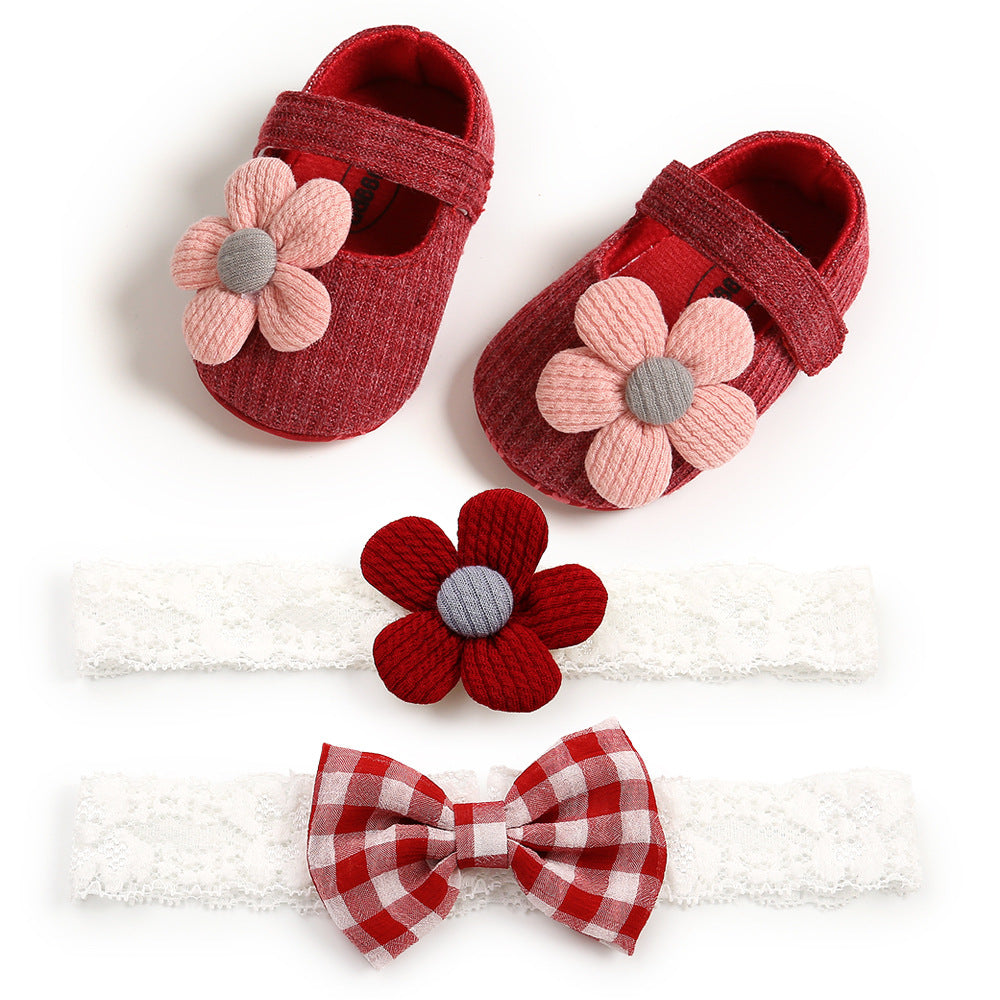 Red baby shoes with pink flower accents, a white lace headband with a red flower, and another lace headband with a red and white checkered bow on a white background.