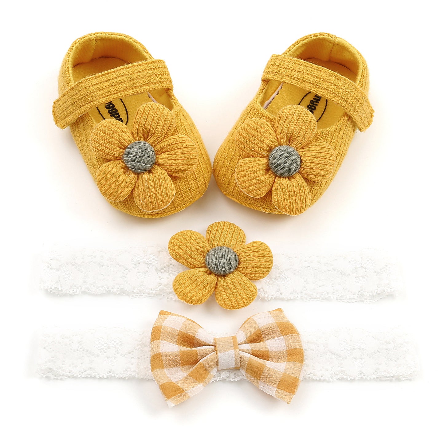 Yellow baby shoes with flower accents, a matching flower hairband, and a white lace headband with a yellow plaid bow, arranged on a white background.