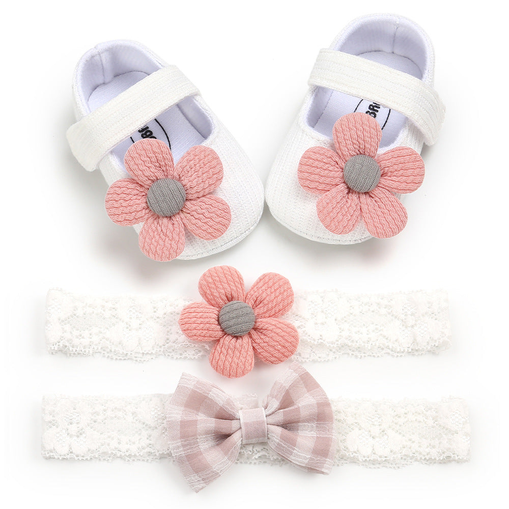 White baby shoes with pink knit flowers. Two lace headbands below: one with a matching pink flower, the other with a soft pink plaid bow.