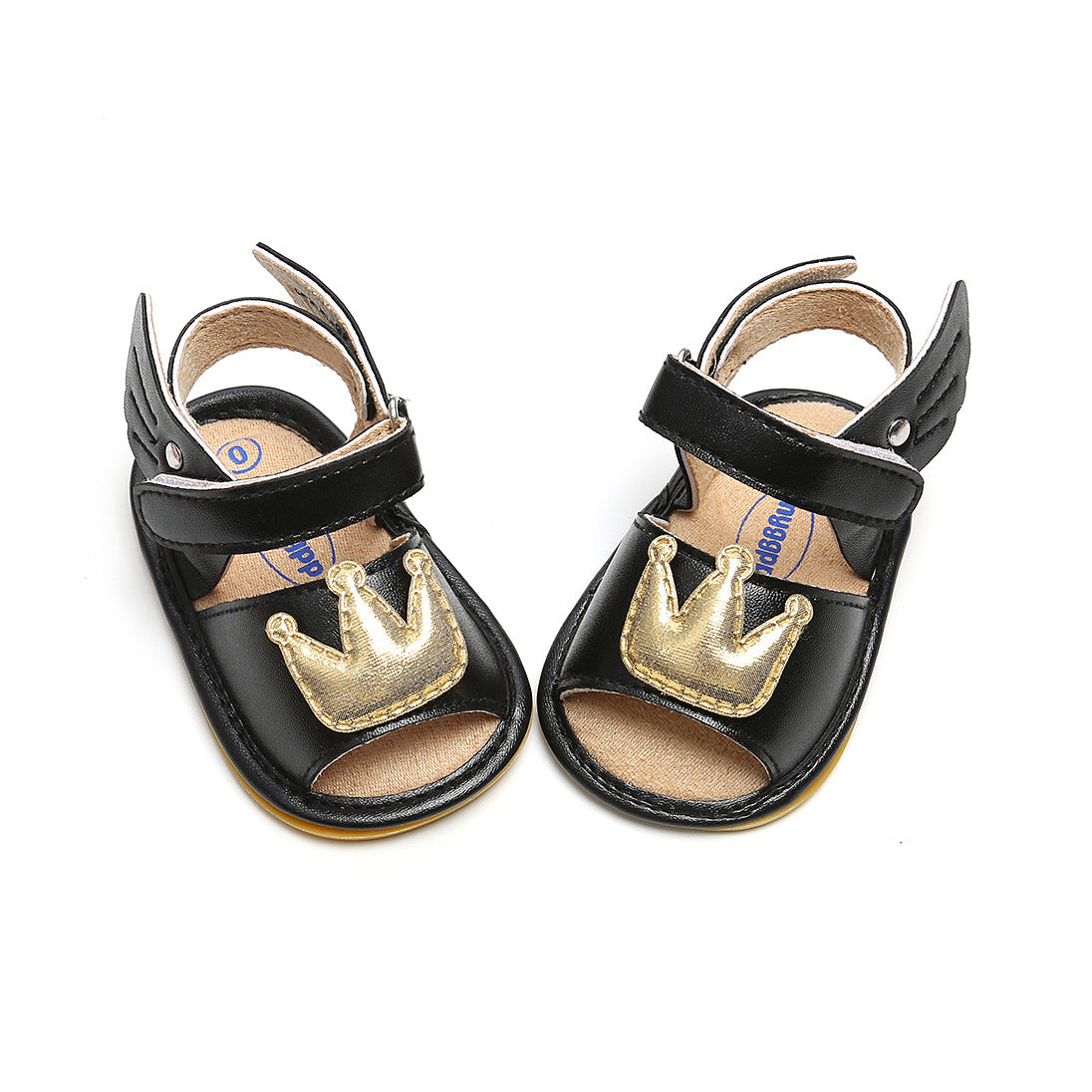 Black children's sandals with ankle straps and gold crown decorations on the front, viewed from above on a white background.