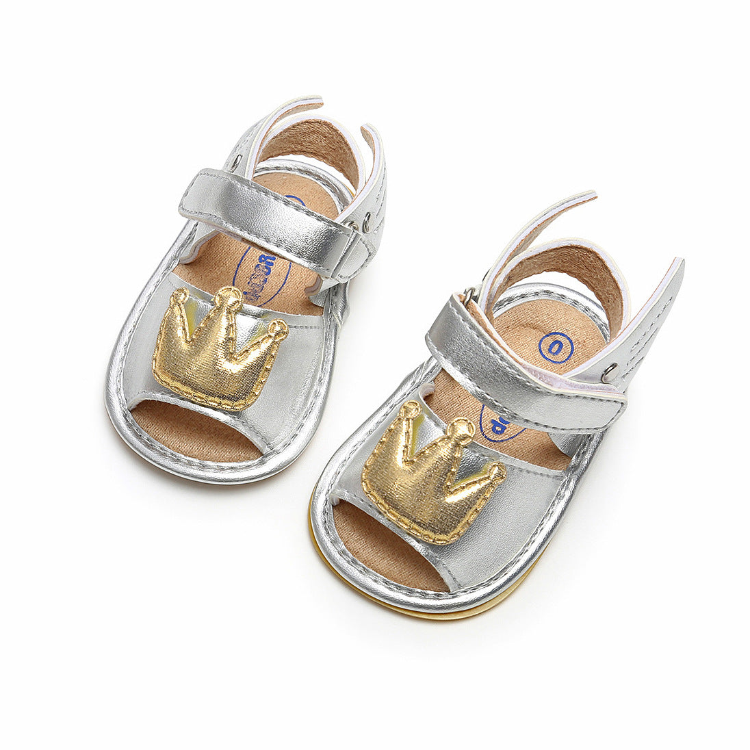 Silver baby sandals with velcro straps and gold crown decals on the toes, shown against a white background.