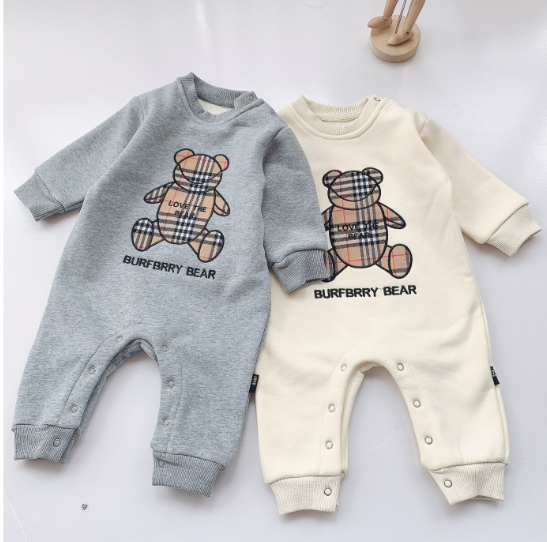 Two baby onesies are displayed side by side on a flat surface. The left onesie is gray, and the right onesie is cream-colored. Both have a bear design with "BURFBRRY BEAR" text.