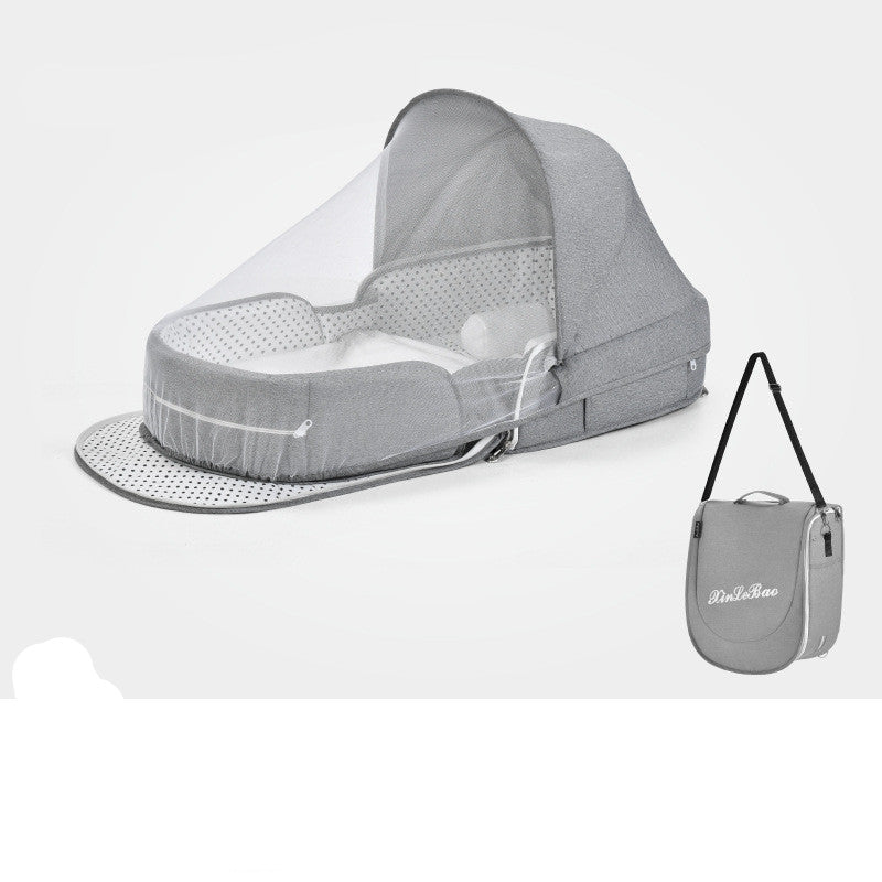 Gray portable baby bed with a mosquito net and polka dot design, shown with a matching carrying bag featuring a shoulder strap, displayed against a white background.