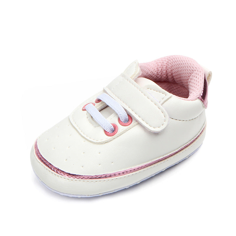 White baby shoe with pink accents, featuring a hook-and-loop strap and lace-up design for easy fastening. The interior is lined with pink mesh for added comfort.