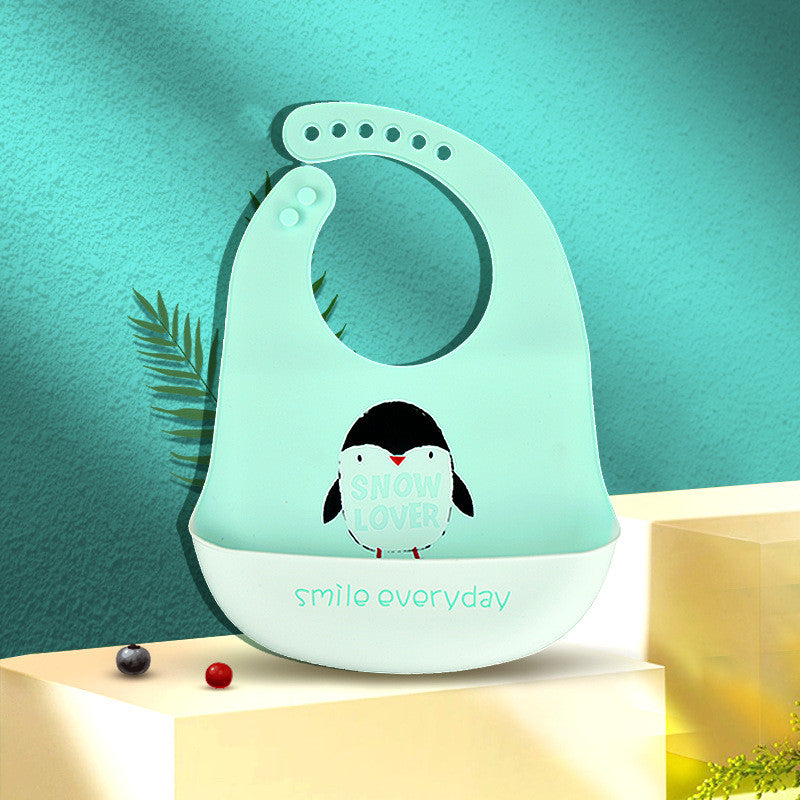 A light turquoise bib with a penguin design and text "SNOW LOVER" is draped over a ledge. Below, it reads "smile everyday" in mint green on a white background.