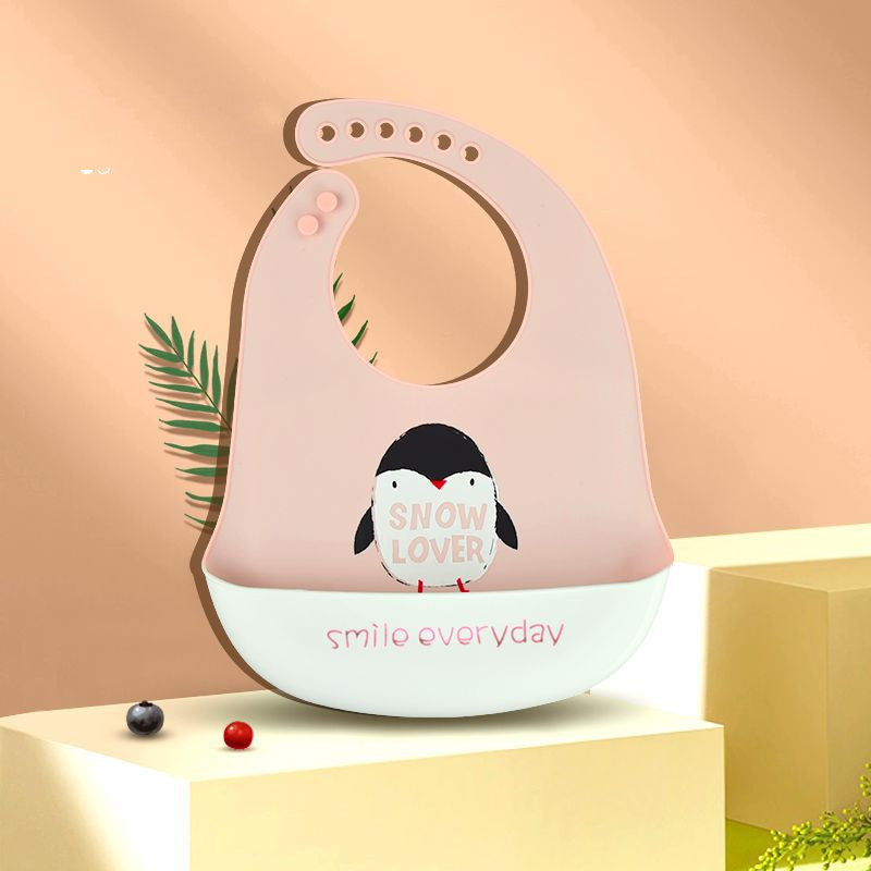 Pink silicone bib with “Snow Lover” penguin design and “smile everyday” text on a beige background. Decorated with a fern leaf, and red and black beads.