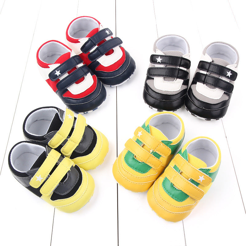 Colorful baby shoes are arranged on a white surface: red and navy, black and white, black and yellow, green and yellow with Velcro straps adorned with stars.