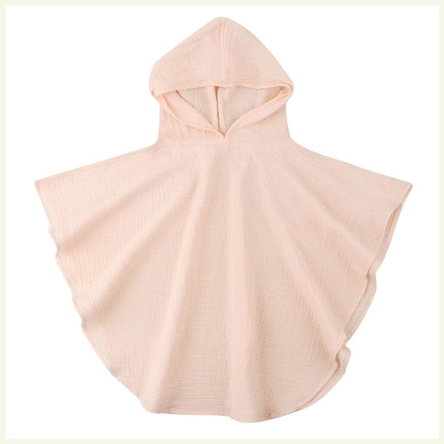 Cream-colored, hooded muslin poncho with a loose, flowing design and rounded edges, perfect for lightweight coverage.
