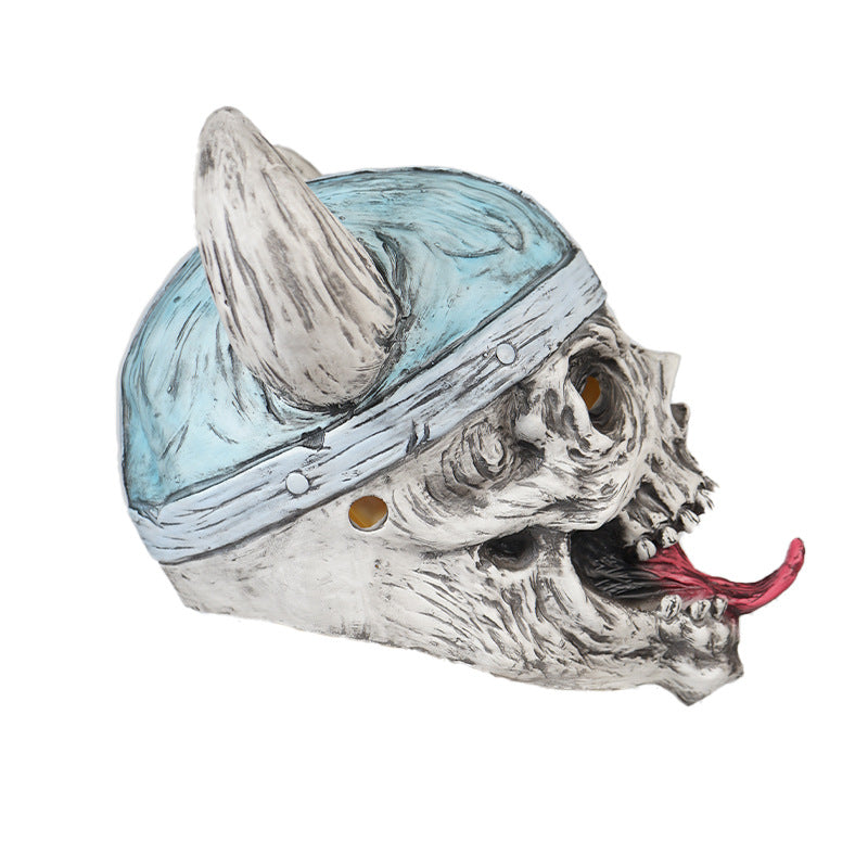 A detailed skull mask with a comical expression, featuring a blue helmet with horns and a protruding red tongue. The mask has exaggerated textures and hollow eye sockets.