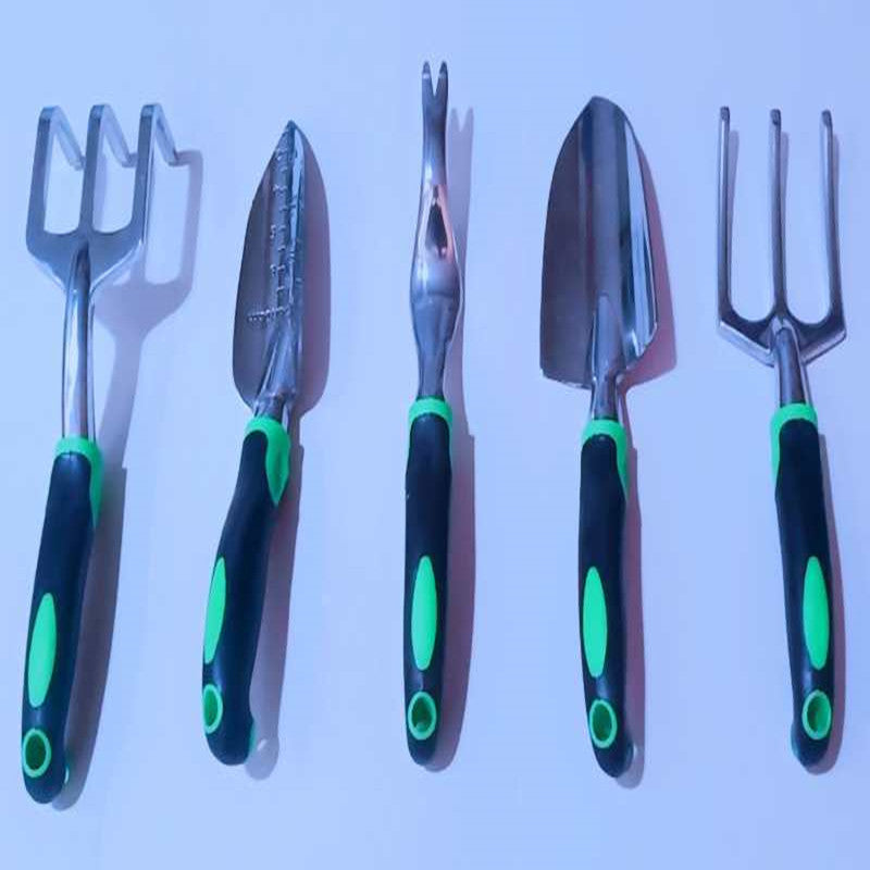 A set of five gardening tools with black and green ergonomic handles, including forks and trowels, laid out side by side on a light surface.