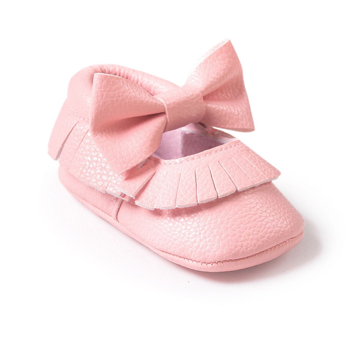 Pink baby shoe with a large bow and fringe details, made of textured material. The shoe has a soft, rounded design, tailored for comfort and style.