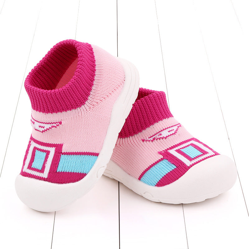 Pink and blue children's slip-on socks with white soles, featuring geometric patterns. The design includes square and line motifs in contrasting colors.