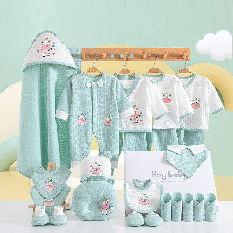 Pastel green and white baby clothing set with cow designs, including onesies, tops, pants, bibs, hat, mittens, blanket, and a gift box. Displayed against a soft background.