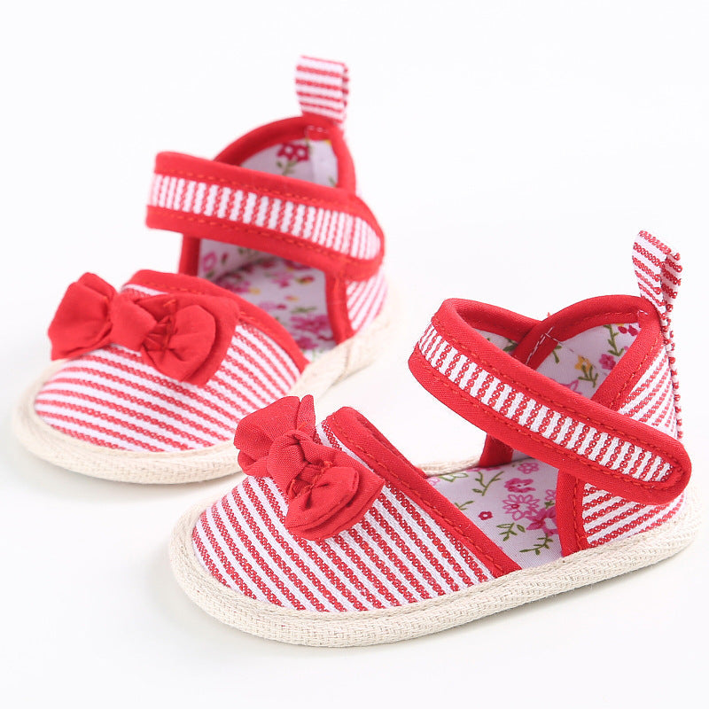 Red and white striped baby shoes with bows, featuring floral-patterned insoles and hook-and-loop straps. They have soft soles and are placed on a white background.