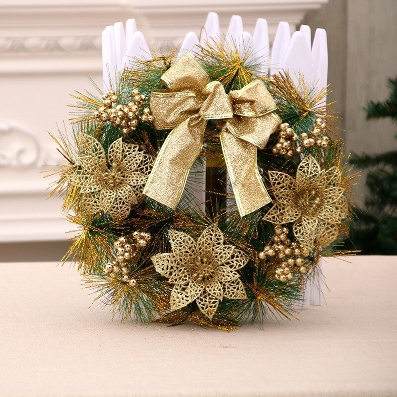 Festive wreath adorned with gold mesh flowers, sparkling gold berries, and a large gold bow, set against a backdrop of green and gold foliage.