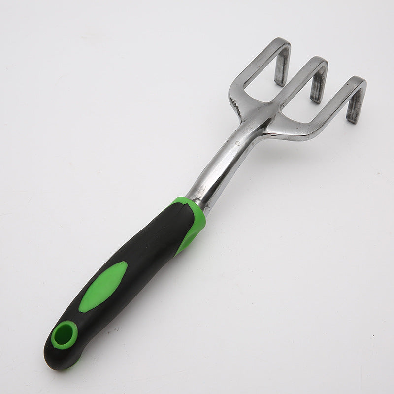 A metal hand rake with three prongs and a black and green ergonomic handle for gardening, placed on a white background.