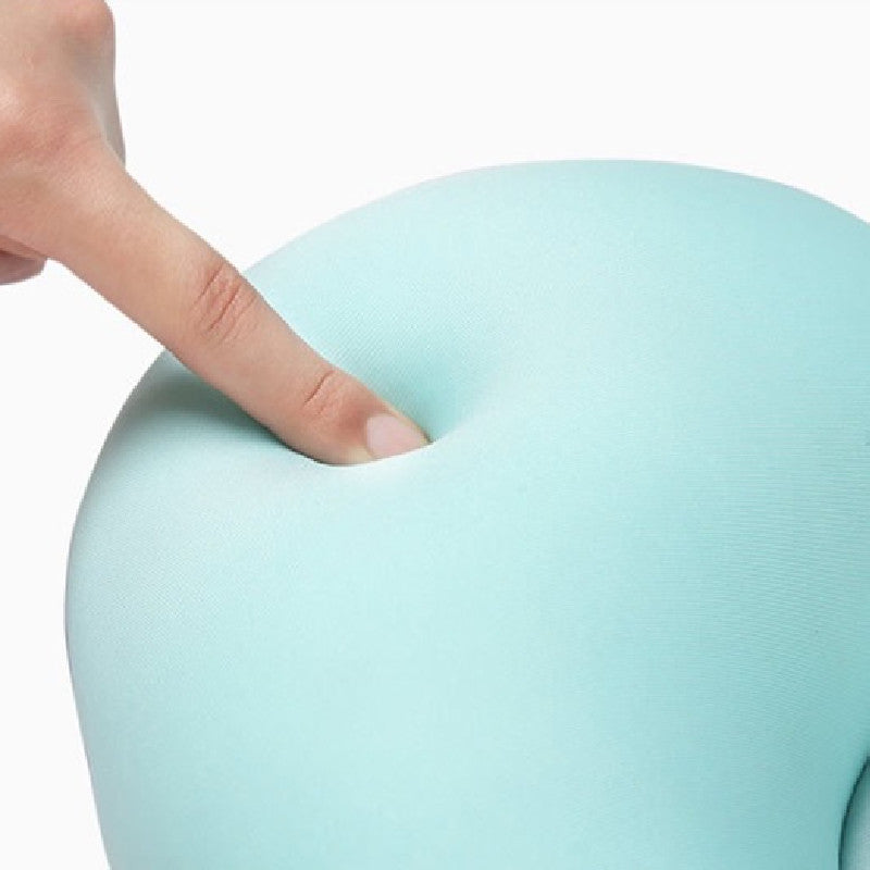 A finger presses into a light blue, soft, foam-like material, creating an indentation. The background is plain white, highlighting the texture and color contrast.