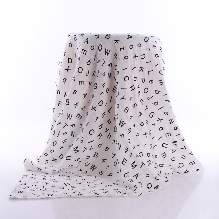 White fabric draped over a stool is covered in scattered black letters in various fonts and orientations, creating a modern, abstract look against a bright background.