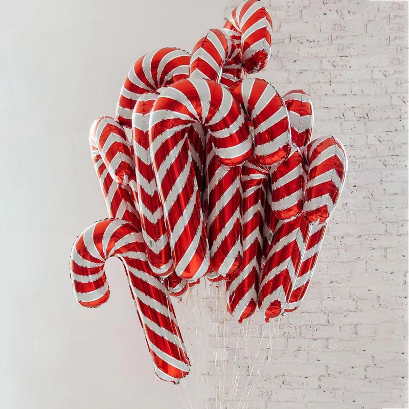 A cluster of shiny, red-and-white striped candy cane balloons against a light gray brick wall, creating a festive and whimsical atmosphere.