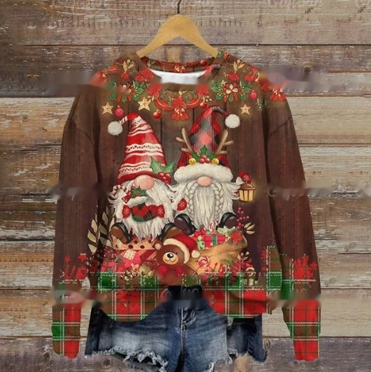 Festive sweater featuring two whimsical gnomes with beards and red hats surrounded by Christmas greenery and gifts. Worn over denim shorts, hung on a wooden background.