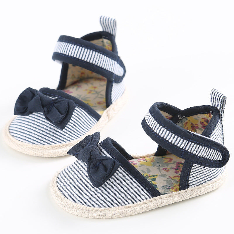Baby shoes with navy and white stripes, decorated with bows on the front. The shoes have a floral inner lining and Velcro straps, perfect for a stylish and comfortable fit.