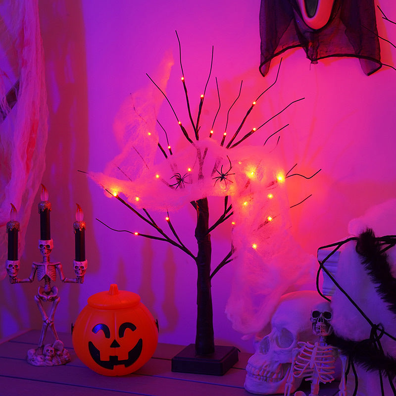 Halloween scene with glowing tree wrapped in cobwebs and spiders. A jack-o'-lantern, skulls, and skeleton candle holders add spooky flair. Warm purple and orange lighting.
