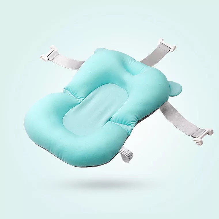A teal baby bath pillow with adjustable straps, designed to cradle and support the infant's head and body. The pillow features a soft and contoured shape to ensure comfort.