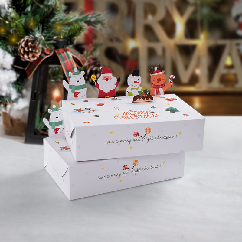 Festive Christmas scene with decorated gift boxes adorned with cartoon characters like a bear, Santa, snowman, and reindeer, set beside a lantern and Christmas tree.