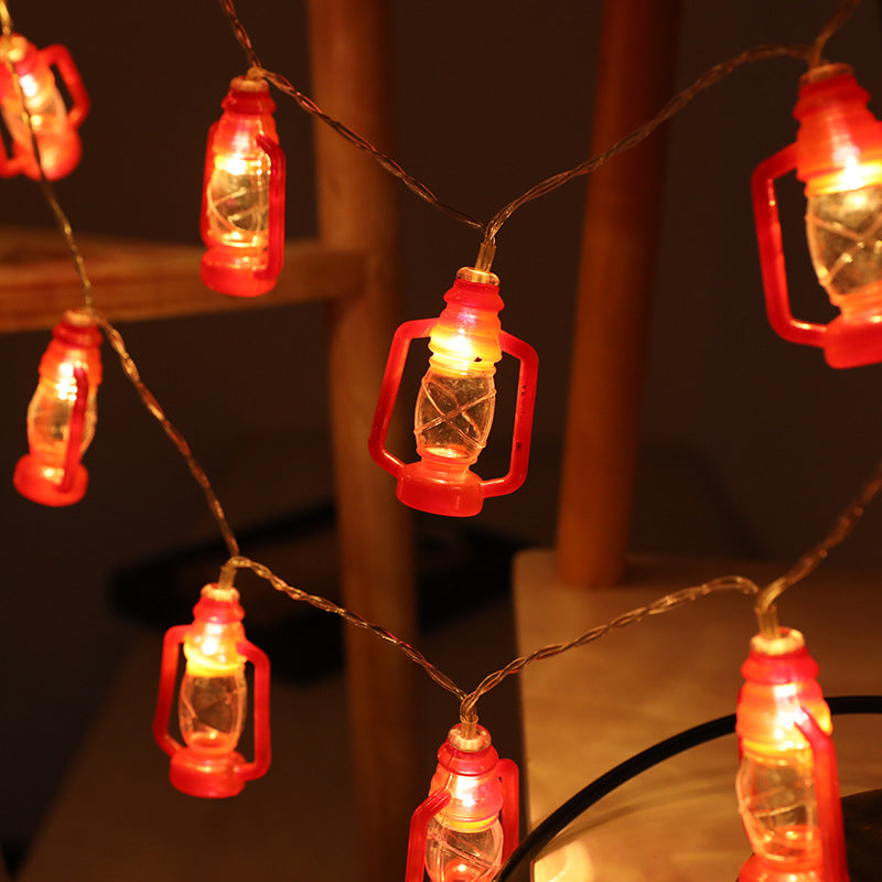 String lights designed as small red lanterns with glowing bulbs, hanging and illuminating a cozy space with warm light.