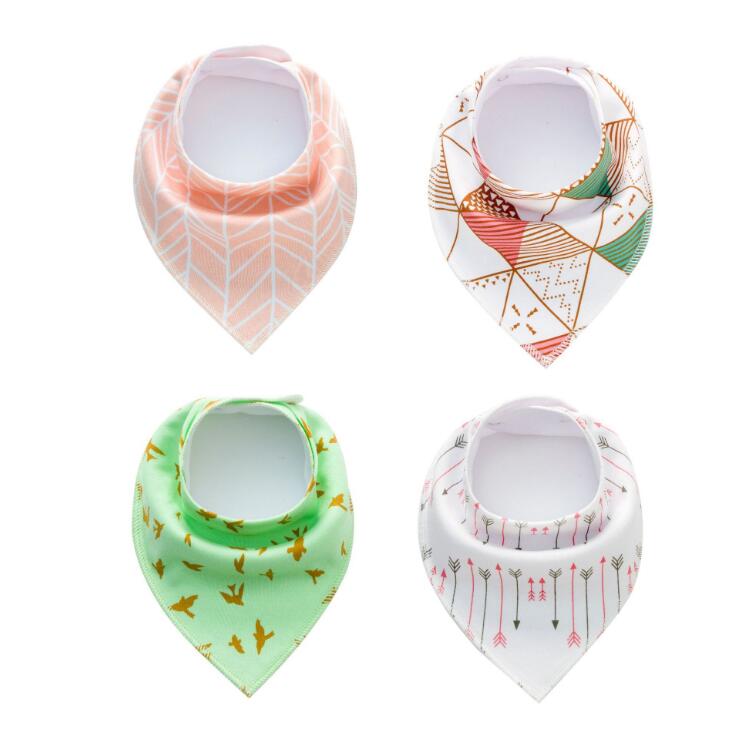 Four baby bibs arranged in a grid. Designs include peach with chevrons, white with orange and green geometric shapes, green with birds, and white with pink and green arrows.