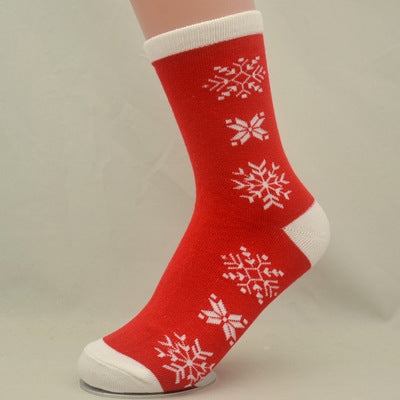 Red sock with white snowflake patterns, featuring white cuffs, heel, and toe. Displayed on a mannequin foot against a plain background.